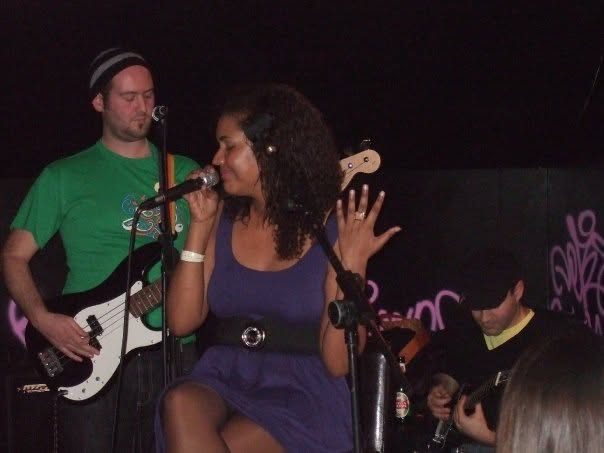 Singer in a purple dress with the band in a bar
