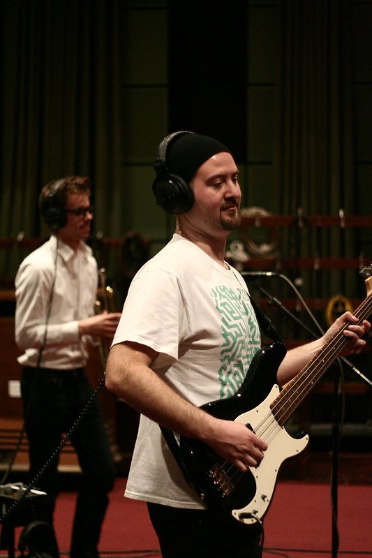 Bassist in headphones with a trumpeter behind